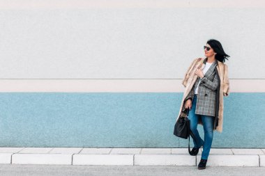 Kürk ceketli ve kot pantolonlu modern orta yaşlı kadın.