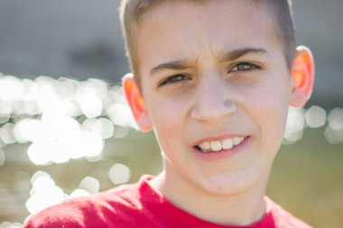 Dışarıda kameraya bakan genç bir çocuğun yakınına.