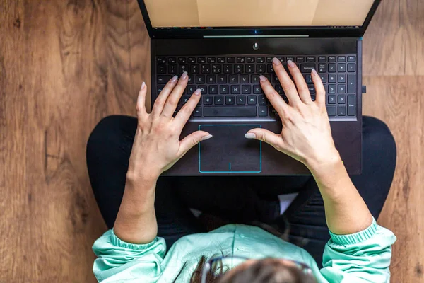 Top view of a woman working on her laptop at home