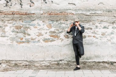 Genç hippi adam eski, eski bir kamerayla fotoğraf çekiyor. Boşluğu kopyala