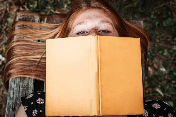 Horní Pohled Dospívající Zrzavou Studentku Ležící Lavičce Držící Knihu Nad — Stock fotografie