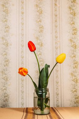 Cam kavanozda üç kırmızı ve sarı lale var. Retro titreşimler. Boşluğu kopyala