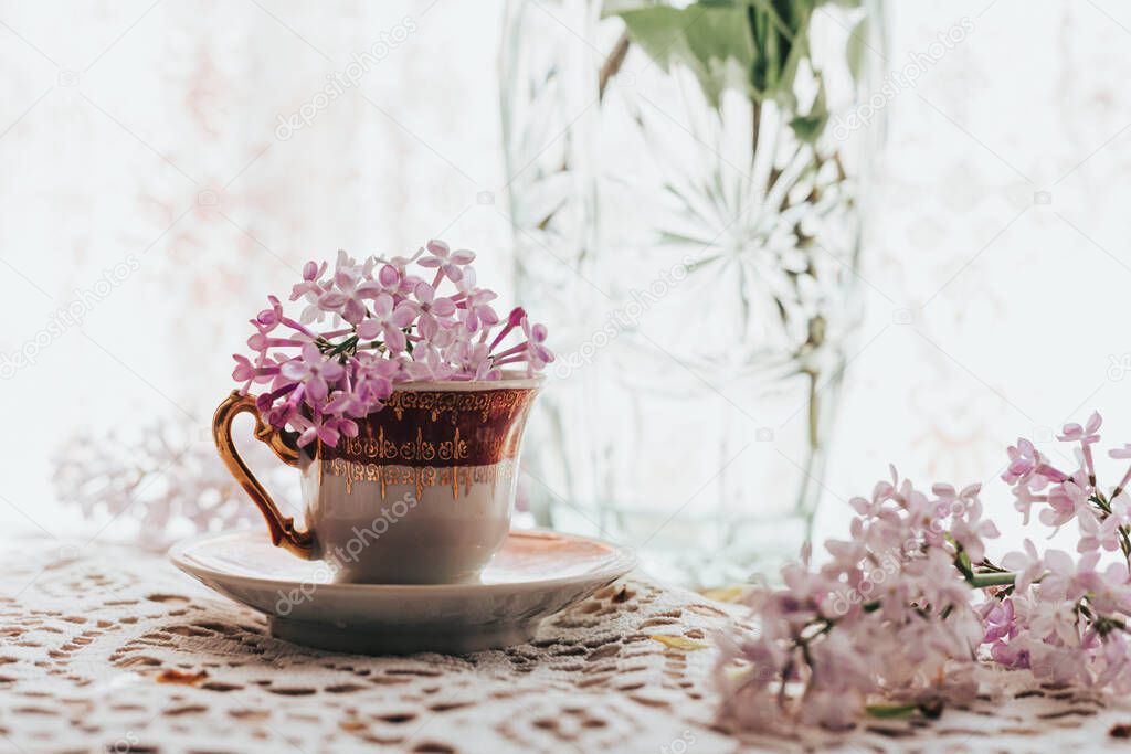 Retro tea cup with lilac flowers in it. Home decoration. Springtime vibes. Space for text