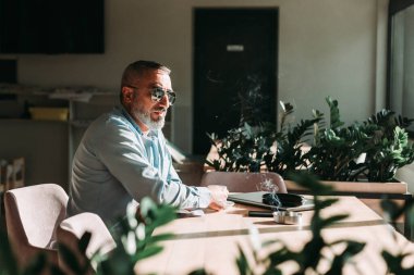 İlk sabah kahvesini içen orta yaşlı sakallı bir adam. İş adamları