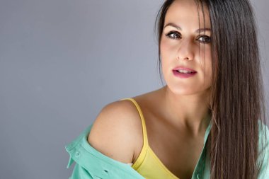 Genç, esmer kız gri arka planda izole edilmiş. Boşluğu kopyala