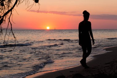 Yunanistan 'da güzel bir gün batımı ve yürüyen bir kadın silueti. Yaz manzarası