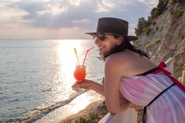 Deniz kenarında kokteyl içen orta yaşlı güzel bir kadın.