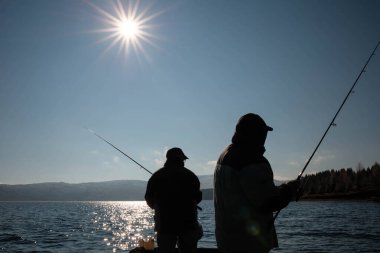 Gölde balık tutan iki balıkçının silueti.