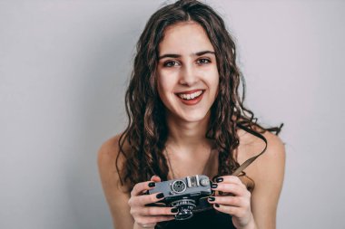 Güzel genç kız elinde eski bir retro film kamerası tutuyor. İzole, beyaz, gri arkaplan