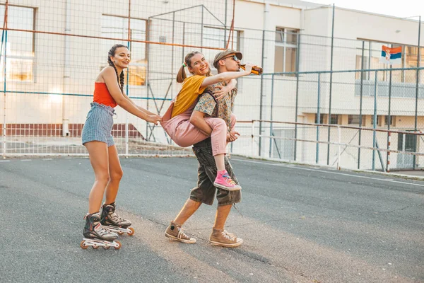 Skupina Přátel Poflakuje Venku Jedna Holka Jede Kamarádce Druhá Kolečkách — Stock fotografie