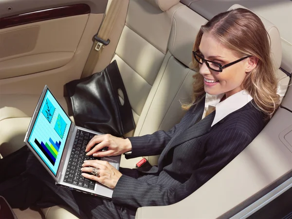 Businesswoman in her car with laptop — Stock Photo, Image