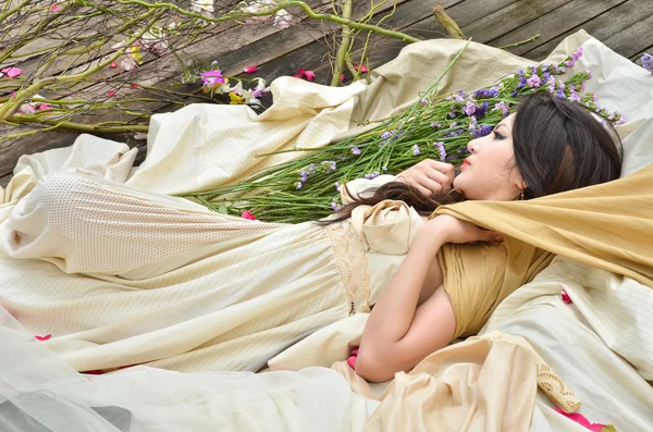 Unga vackra kvinnan sova med blommor utomhus — Stockfoto