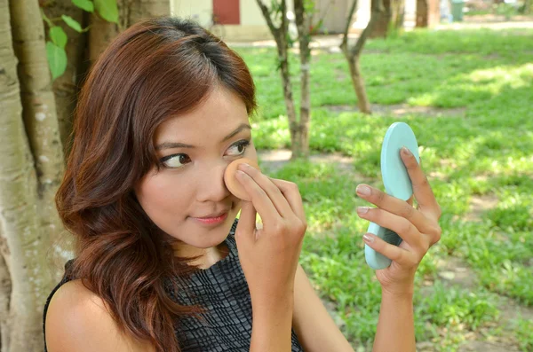 Красивая женщина наносит макияж с ее косметикой в парке — стоковое фото