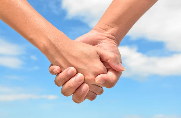 Partner hand between a man and a woman on blue sky background — Stock Photo, Image