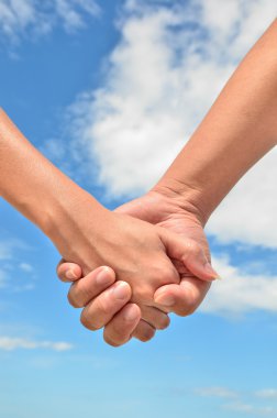 Bir erkek ve bir kadın mavi gökyüzü arka plan üzerinde arasındaki ortak el
