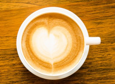 Bir fincan kahve kalp şeklinde ahşap arka plan üzerinde