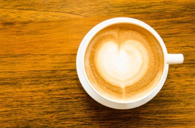 Bir fincan kahve kalp şeklinde ahşap arka plan üzerinde