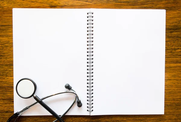 Stethoscope with open blank book on grungy wood background — Stock Photo, Image