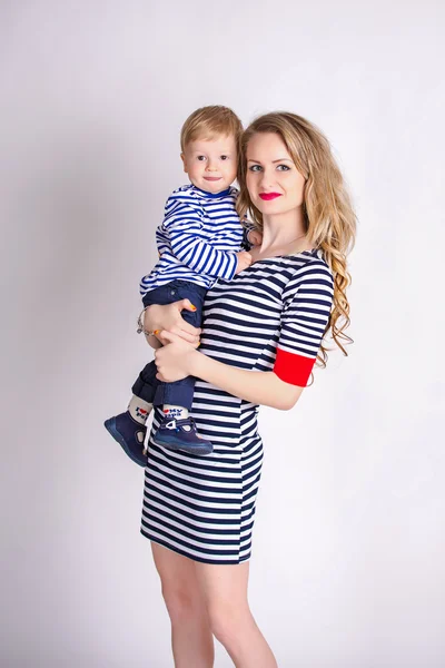 Madre con su hijo en brazos, rubia, sonriente, ropa a rayas, la familia marinera —  Fotos de Stock