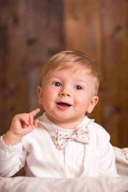 ahşap arka plan bir tahta sandalyede oturan sarışın bebek beyaz takım elbise beyaz çorap. yanındaki küçük bir ördek yavrusu