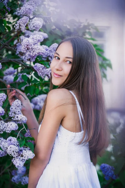 Fiatal gyönyörű lány a fehér sundress álló fa, virág, fa tsvettsschee, rózsaszín virágok, tavaszi, nap, boldogság, gyengédség, lila közelében — Stock Fotó