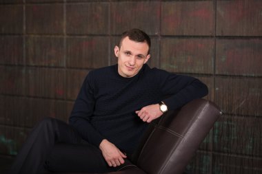 wealthy man, dark background, short-haired man, businessma, a man in a dark  sweater, blazer, looking directly into the camera, stern look, business, brick wall, dark background, red brick, bright smile,