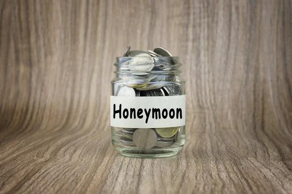 Glass jars with coins labeled Honeymoon. Financial Conceptual