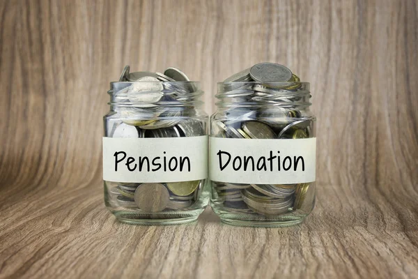 Dos frascos de vidrio con monedas etiquetadas como Pensión y Donación. Conceptual financiero —  Fotos de Stock