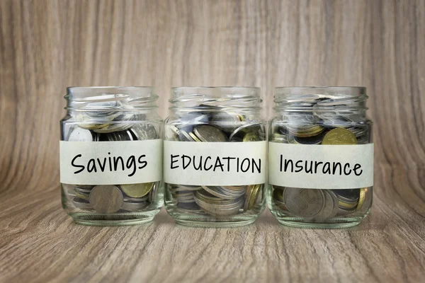 Monedas en tarro de vidrio con etiqueta de ahorro, educación y seguro. Concepto financiero —  Fotos de Stock