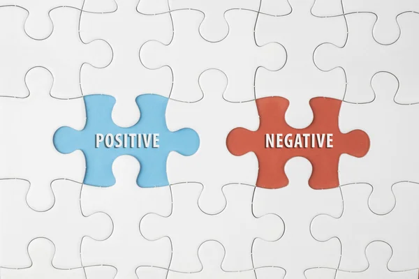 Puzzle auf farbigem Papier Hintergrund mit einem Wort positiv und negativ — Stockfoto