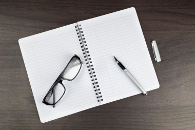Kalem ve güneş gözlüğü ile office masada boş not defteri