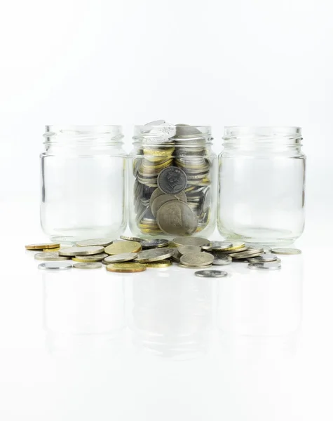 Tarro de vidrio con monedas y 2 tarros vacíos sobre fondo blanco — Foto de Stock