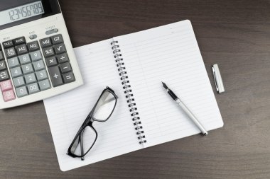 Kalem, hesap makinesi ve gözlük ile office tabloda boş not defteri. Yukarıdan görüntülemek