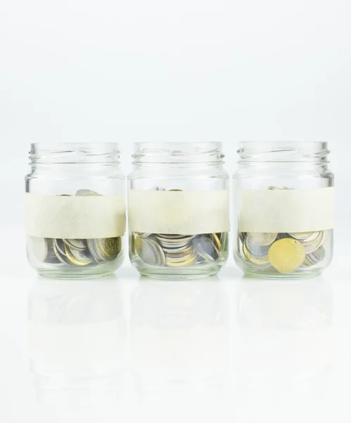 Un'etichetta vuota di vasi di vetro con monete su sfondo bianco Fotografia Stock