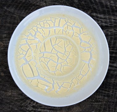 Milk cream dried in a white porcelain saucer and formed an abstract pattern like crackles. Isolated on blac clipart