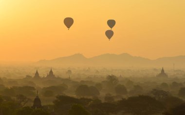Bagan 'da güzel bir gündoğumu sahnesi (Myanmar) antik tuğla tapınaklar ve gökyüzünde uçan sıcak hava balonları kompleksiyle.
