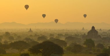 Bagan 'da güzel bir gündoğumu sahnesi (Myanmar) antik tuğla tapınaklar ve gökyüzünde uçan sıcak hava balonları kompleksiyle.