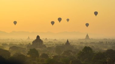 Bagan 'da güzel bir gündoğumu sahnesi (Myanmar) antik tuğla tapınaklar ve gökyüzünde uçan sıcak hava balonları kompleksiyle.