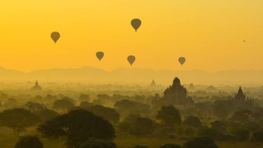 Bagan 'da güzel bir gündoğumu sahnesi (Myanmar) antik tuğla tapınaklar ve gökyüzünde uçan sıcak hava balonları kompleksiyle.