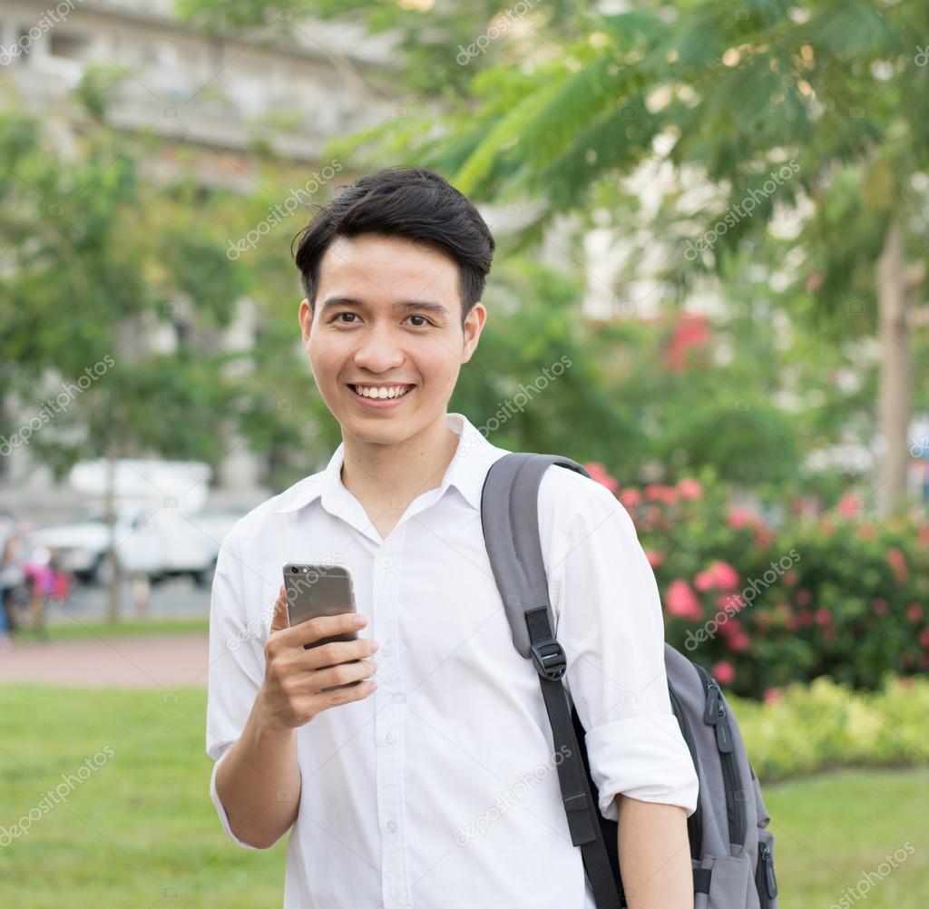 Happy Asian young student using mobile phone