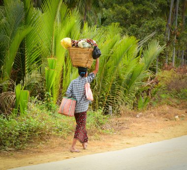 Burmese woman is carrying a bag on her head