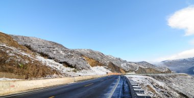 Buz gibi mavi gökyüzü altında karlı yol