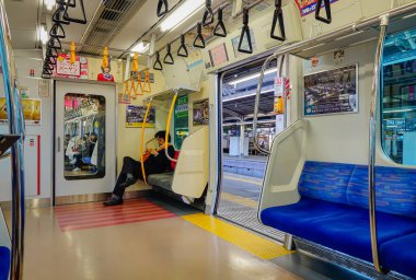 Tokyo, Japonya - 2 Ocak 2016. Japonya 'daki modern Tokyo metro treni, akıllı telefon kullanan yolcularla dolu temiz koltuklar ve tırabzanlar..
