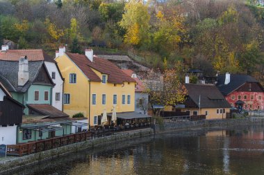 Krumlov, Çek - 24 Ekim 2025. Krumlov, Güney Bohemya, Çek Cumhuriyeti manzaralı, ikonik kale kulesi ve nehir boyunca kırmızı çatılı binalar.