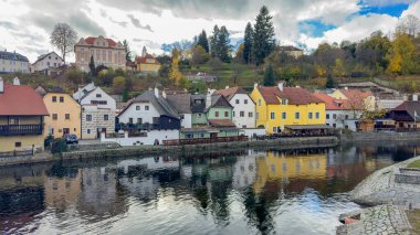 Krumlov, Çek - 24 Ekim 2025. Krumlov, Güney Bohemya, Çek Cumhuriyeti manzaralı, ikonik kale kulesi ve nehir boyunca kırmızı çatılı binalar.