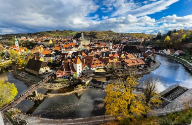 Krumlov, Güney Bohemya, Çek Cumhuriyeti manzaralı, ikonik kale kulesi ve nehir boyunca kırmızı çatılı binalar.