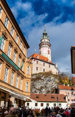 Krumlov, Çek - 24 Ekim 2025. Krumlov, Güney Bohemya, Çek Cumhuriyeti manzaralı, ikonik kale kulesi ve nehir boyunca kırmızı çatılı binalar.