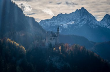Almanya 'nın Bavyera kentindeki karla kaplı dağlarla çevrili Neuschwanstein Şatosu' nun sonbaharda manzarası.