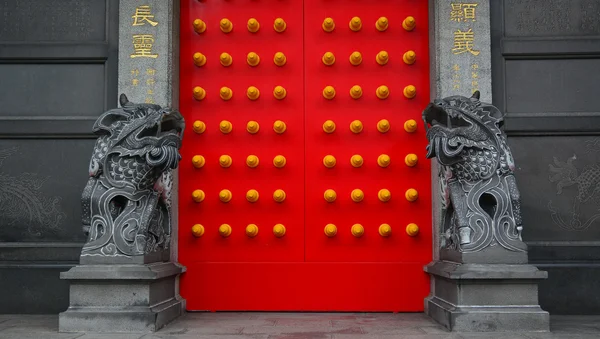 Китайский каменный лев в храме с красной дверью — стоковое фото