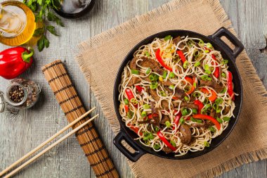 Sığır etli Çin makarnası. Tavada hazır. Ahşap arka plan. Üst görünüm.